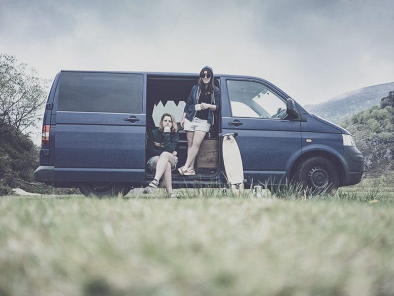 Deux femmes sont assises dans un van avec la porte ouverte dans la campagne