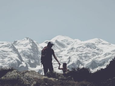 Une femme tient sa fille par la main devant la montagne enneigée