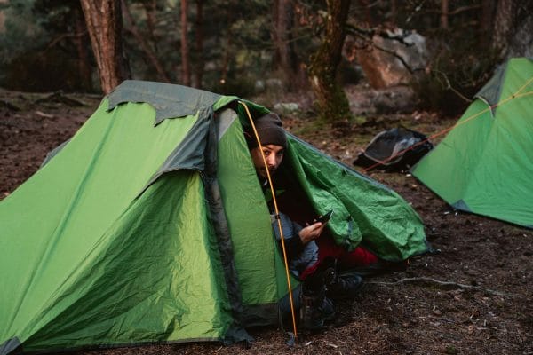un homme sort de sa tente en forêt