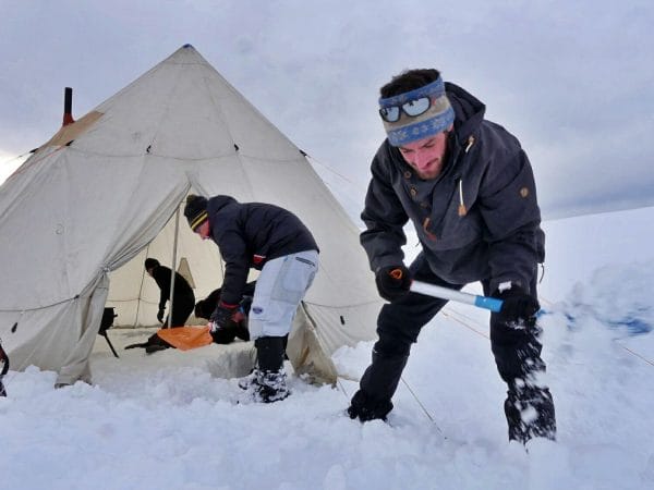 des randonneurs montent leur tente dans la neige