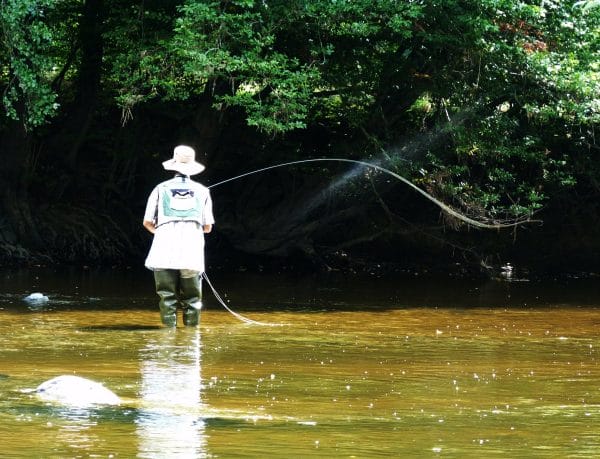 un homme fait de la pêche à la mouche dans une rivière