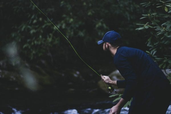 un homme fait de la pêche à la mouche dans une rivière