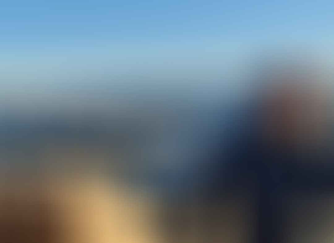 Un homme qui porte un bonnet sourit à la caméra depuis le sommet d'une montagne des Alpes