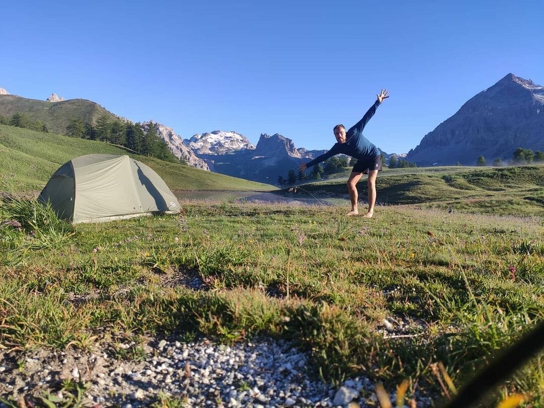 Un homme devant sa tente dans la montagne