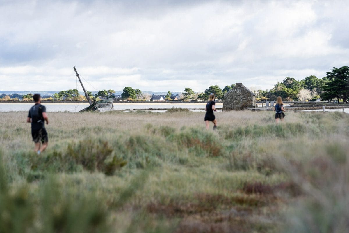 faire le golfe du Morbihan en trail : coureurs dans les marais avec épave de bateau